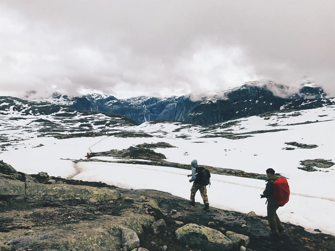 People walk across snow-covered mountains.